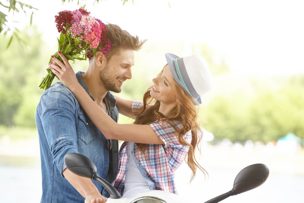 Glückliches Pärchen umarmt sich draußen mit Blumen