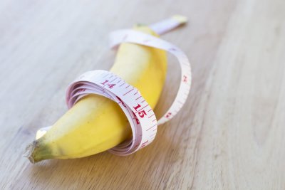 Banane liegt eingewickelt in Maßband auf einem Holztisch