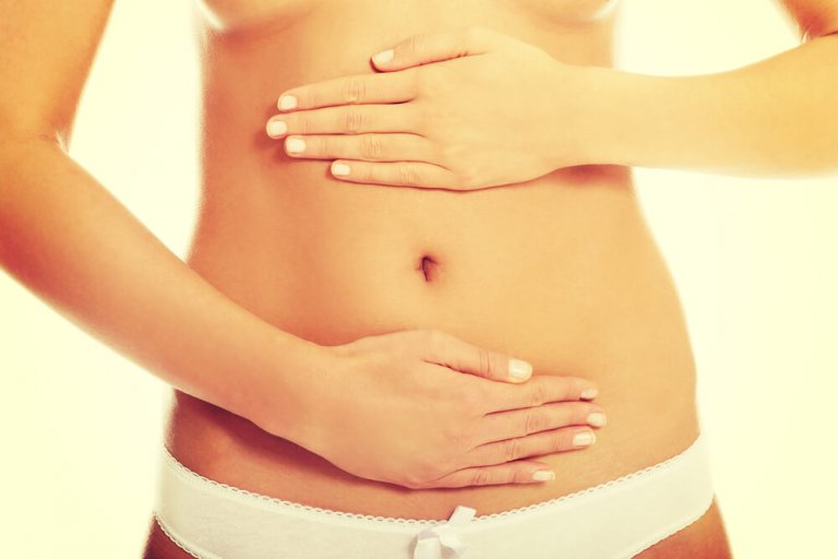 Frau steht mit Bauch zur Kamera und hält sich die Hände über unter den Bauchnabel