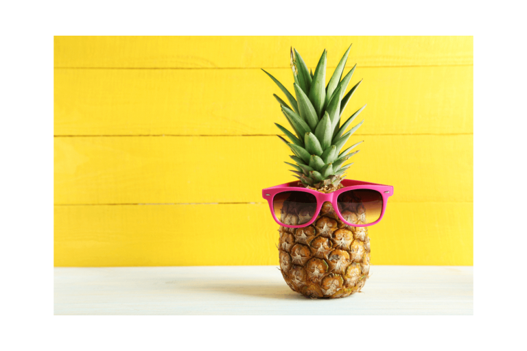 Ananas mit Sonnenbrille vor gelber Wand