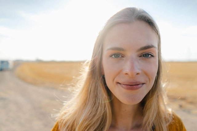 Eine Frau lächelt in die Kamera, die Sonne scheint