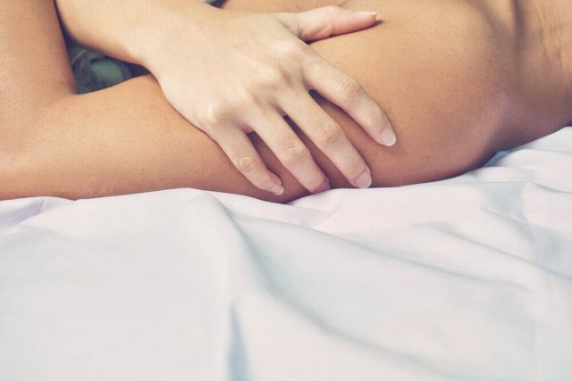 Eine Frau berührt den Arm ihres Partners im Bett
