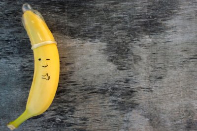 Eine Banane mit Kondom als Mütze, jemand hat ein zwinkerndes Smiley und einen ausgestreckten Daumen darauf gezeichnet