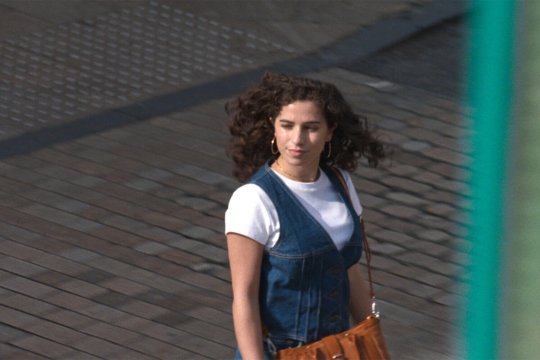 Frau in Jeanskleid die eine Straße überquert